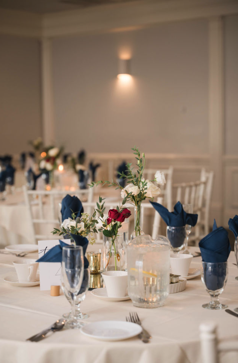 Elegant wedding reception table with floral centerpieces and navy details at Amarante’s Sea Cliff